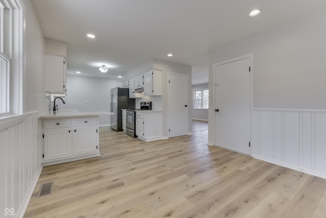 kitchen with white cabinetry, sink, stainless steel appliances, and light hardwood / wood-style floors