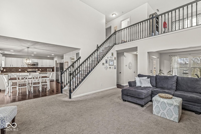 living room featuring a chandelier, dark carpet, and a high ceiling