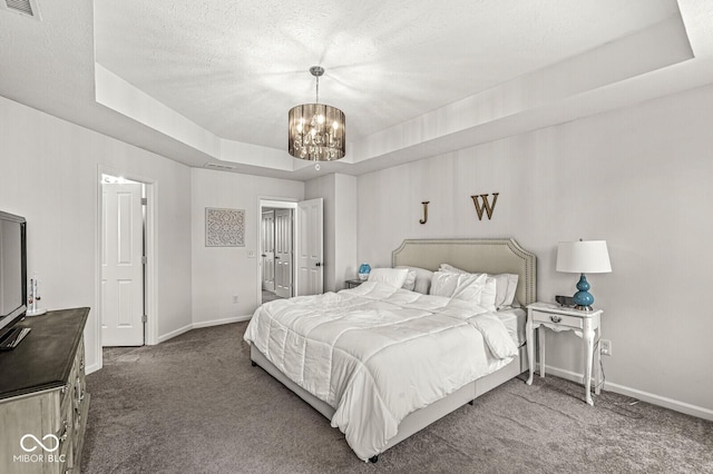 bedroom with a textured ceiling, a notable chandelier, dark carpet, and a tray ceiling