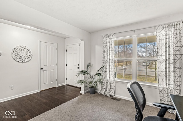 home office with dark hardwood / wood-style floors and a textured ceiling