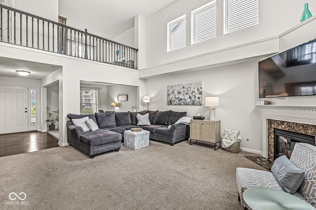 carpeted living room with a fireplace, a high ceiling, and a wealth of natural light