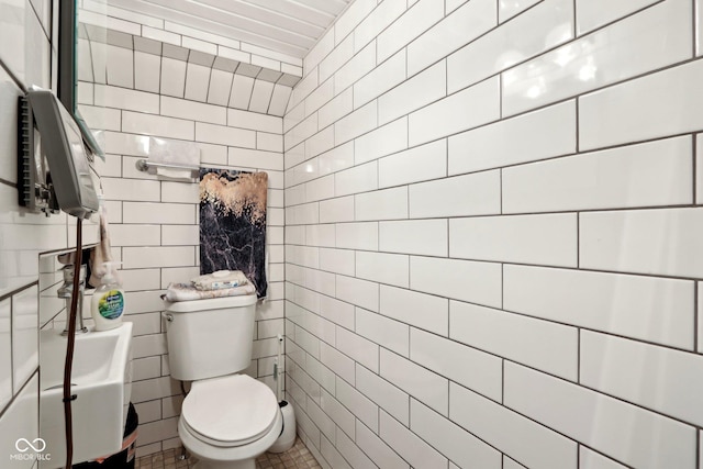 bathroom featuring tile walls and toilet