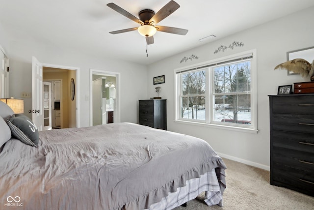 bedroom with ceiling fan, light colored carpet, and ensuite bath