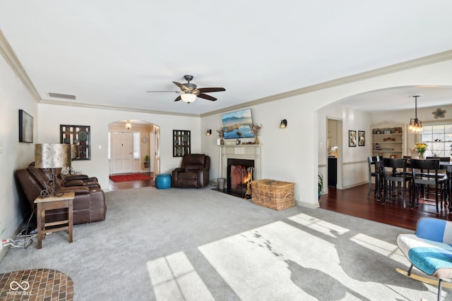 living room with crown molding, ceiling fan, and carpet