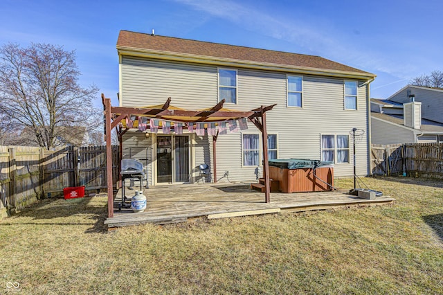 rear view of house featuring a yard, a hot tub, a pergola, and a deck