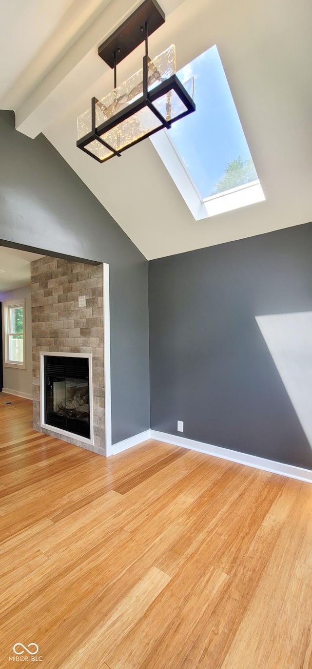 unfurnished living room featuring a fireplace, lofted ceiling with skylight, and light hardwood / wood-style flooring