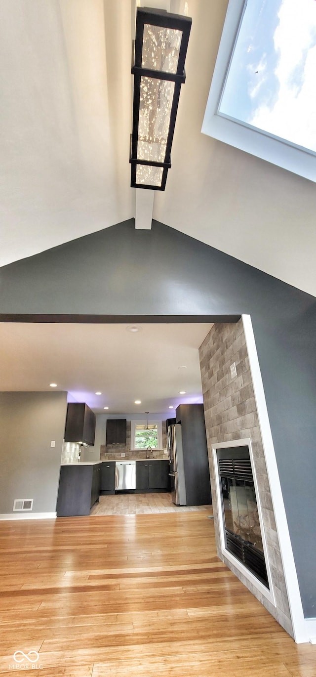 unfurnished living room with vaulted ceiling with beams, a fireplace, light hardwood / wood-style floors, and sink