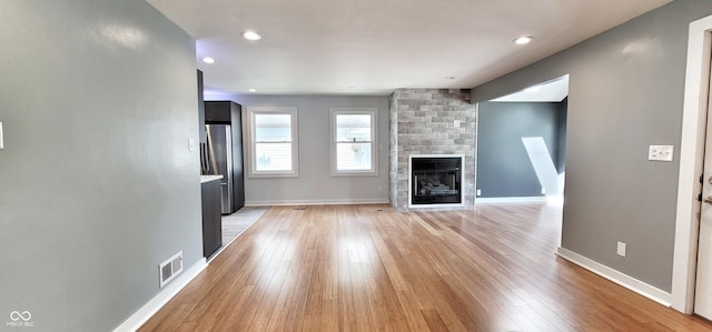 unfurnished living room with a fireplace and light wood-type flooring