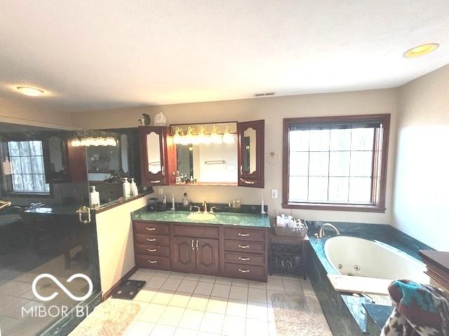 bathroom with plenty of natural light, tiled bath, and vanity