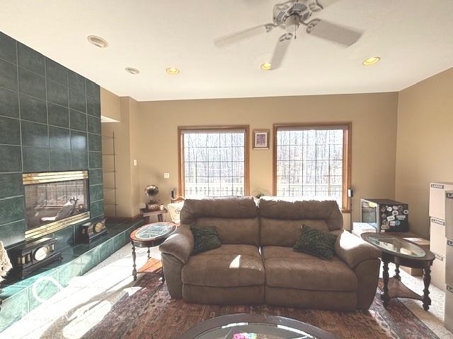 living room featuring a tiled fireplace and ceiling fan