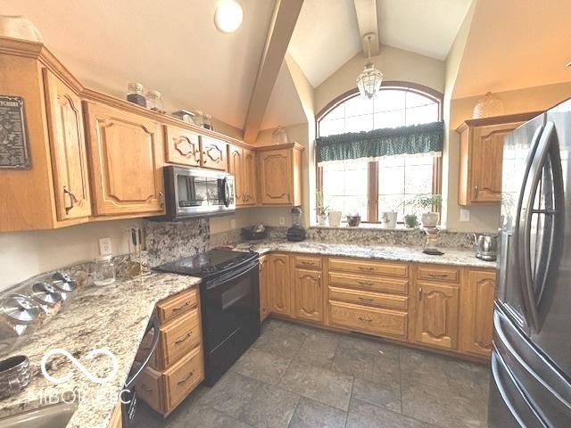 kitchen featuring appliances with stainless steel finishes, light stone countertops, and vaulted ceiling with beams