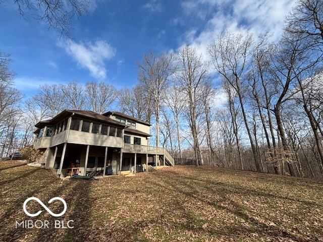 back of house featuring a wooden deck, a yard, and a sunroom