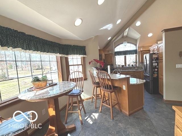 kitchen featuring lofted ceiling, black refrigerator, kitchen peninsula, and a kitchen bar