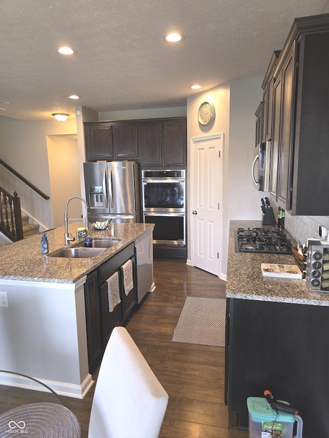 kitchen featuring sink, light stone counters, dark hardwood / wood-style flooring, a kitchen island, and stainless steel appliances