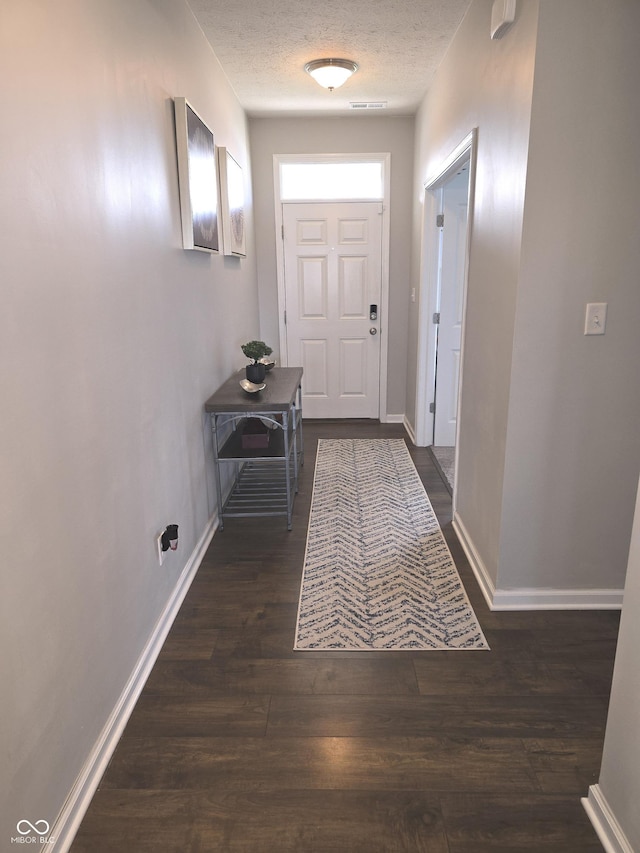 doorway featuring dark wood-type flooring and a textured ceiling