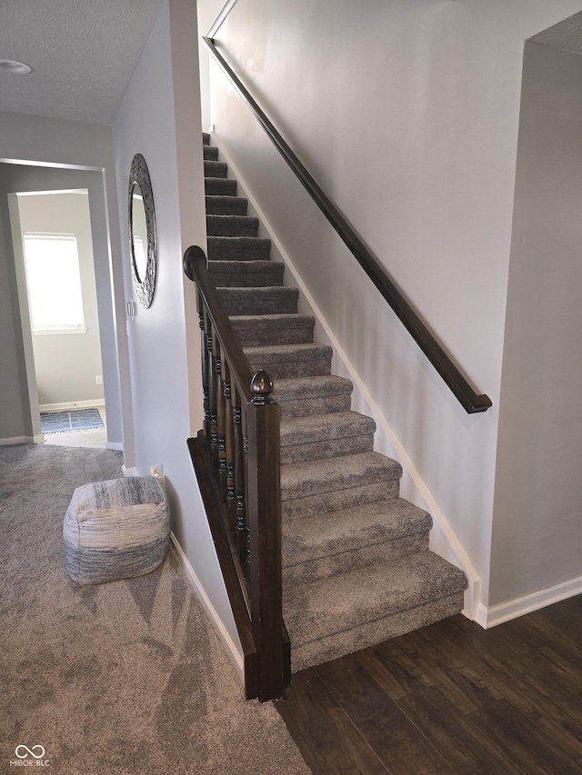 stairs featuring wood-type flooring and a textured ceiling