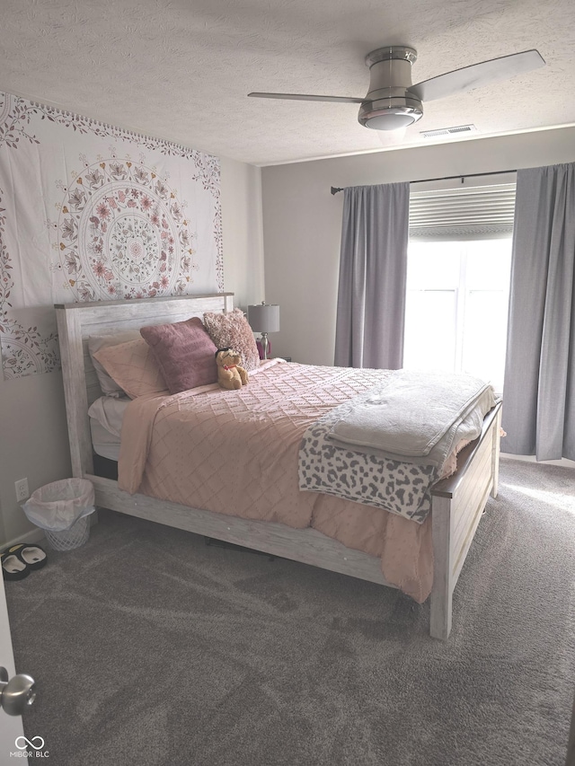 bedroom with ceiling fan, carpet floors, and a textured ceiling