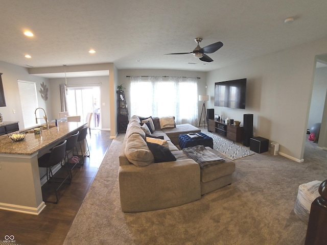 living room featuring sink, dark wood-type flooring, and ceiling fan