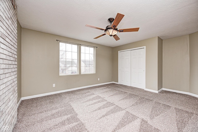 unfurnished bedroom featuring carpet, a closet, ceiling fan, a textured ceiling, and baseboards