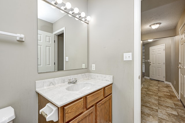 bathroom featuring toilet, baseboards, a textured ceiling, and vanity