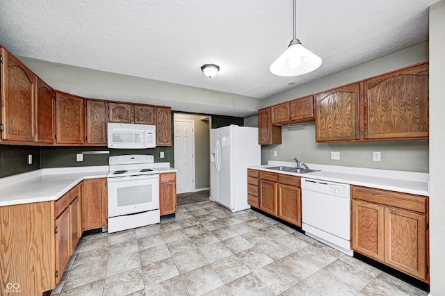 kitchen featuring brown cabinetry, white appliances, light countertops, and a sink