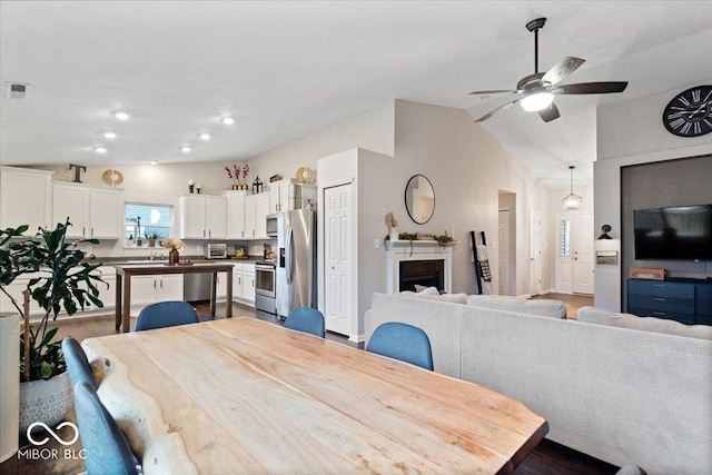 dining space featuring ceiling fan, wood-type flooring, and vaulted ceiling