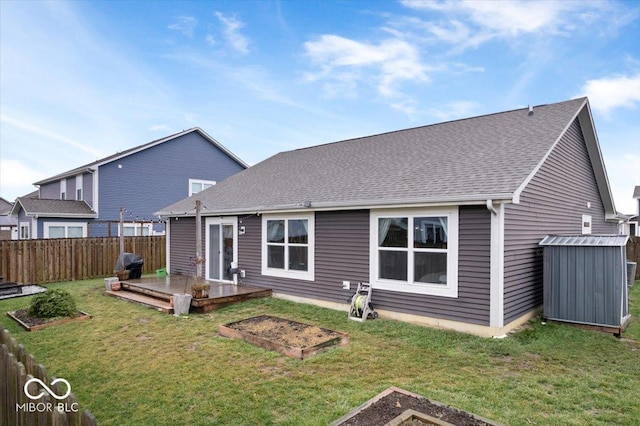 rear view of house with a wooden deck and a lawn