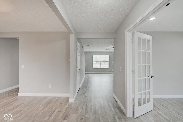 corridor featuring light hardwood / wood-style flooring and a textured ceiling