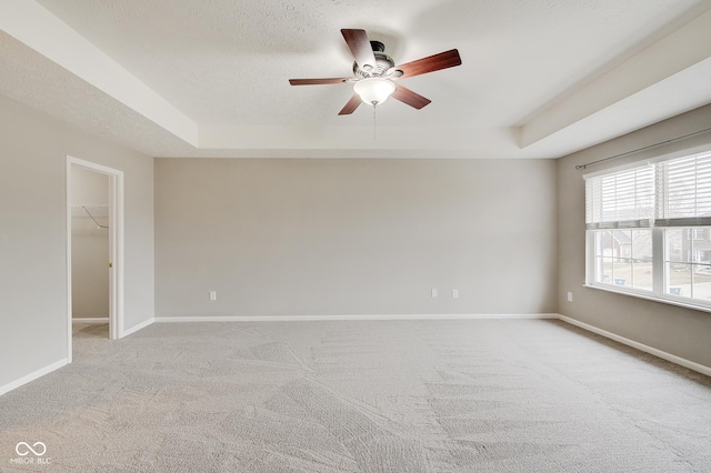 carpeted spare room with ceiling fan, a raised ceiling, and a textured ceiling