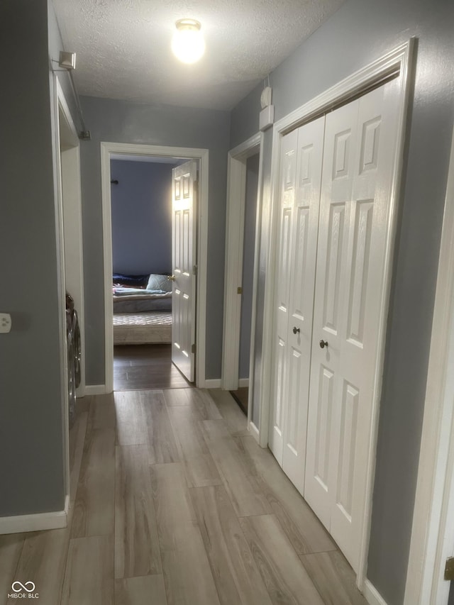 corridor with light hardwood / wood-style flooring and a textured ceiling