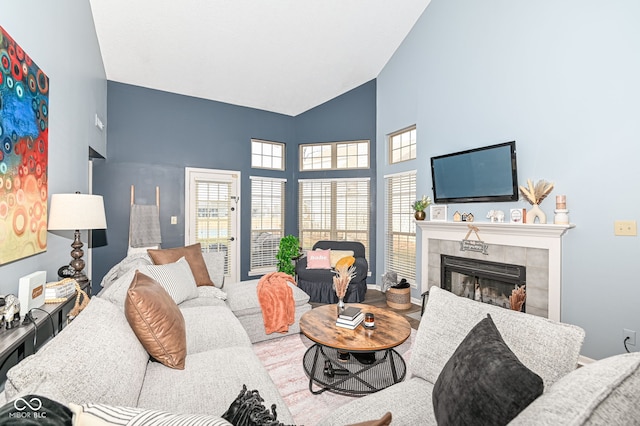 living room featuring high vaulted ceiling and a tile fireplace