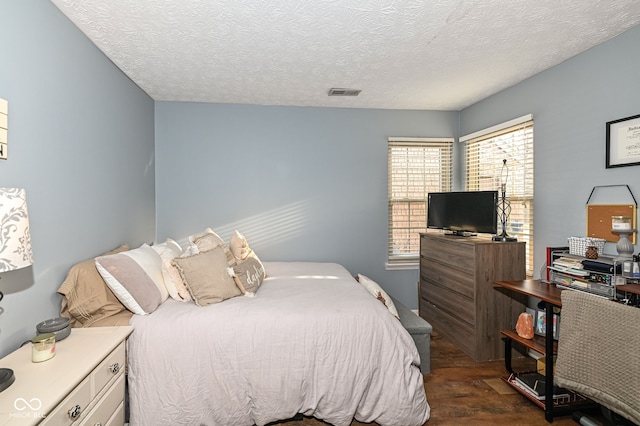 bedroom with dark hardwood / wood-style floors and a textured ceiling