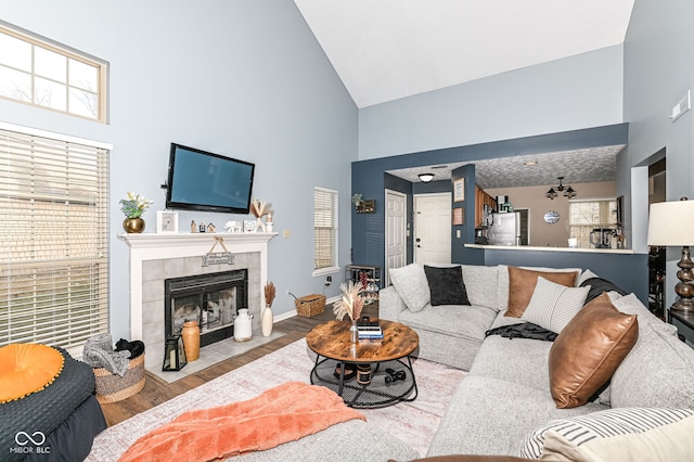 living room featuring a tiled fireplace, hardwood / wood-style floors, and high vaulted ceiling