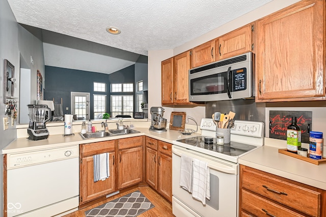 kitchen with sink, white appliances, light hardwood / wood-style flooring, and a textured ceiling