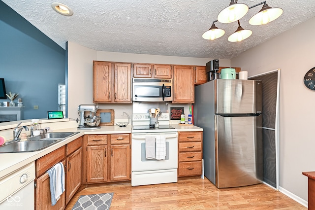 kitchen with sink, decorative light fixtures, a textured ceiling, light wood-type flooring, and stainless steel appliances