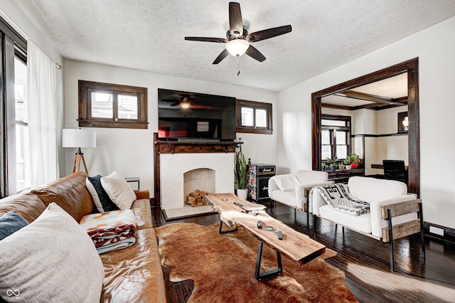 living room featuring hardwood / wood-style floors, a fireplace, a textured ceiling, and ceiling fan