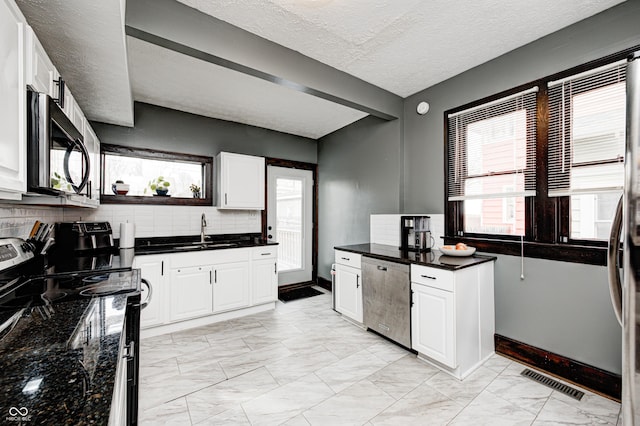 kitchen featuring white cabinetry, sink, backsplash, and appliances with stainless steel finishes