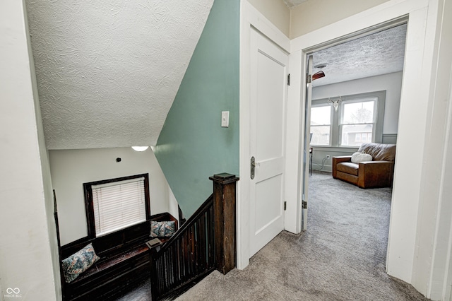 hallway with light colored carpet and a textured ceiling