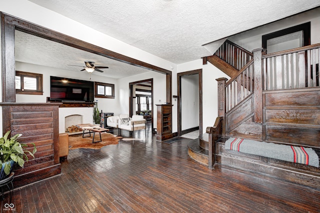 interior space with a brick fireplace, hardwood / wood-style flooring, a textured ceiling, and a healthy amount of sunlight