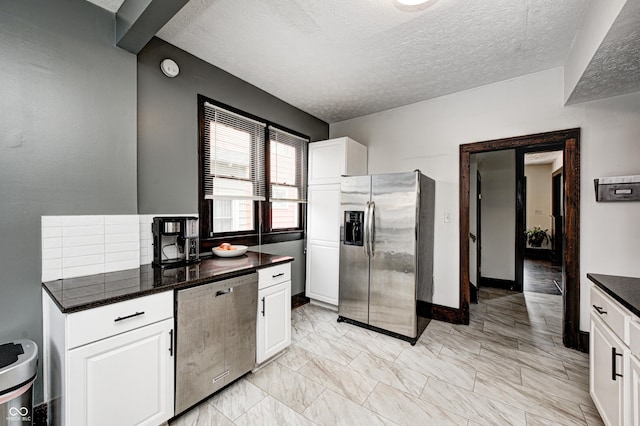 kitchen featuring stainless steel appliances, white cabinetry, and a textured ceiling