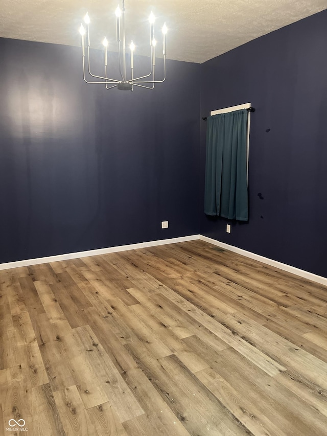 spare room with a notable chandelier and light hardwood / wood-style floors