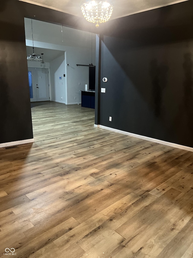 spare room with hardwood / wood-style flooring and a notable chandelier