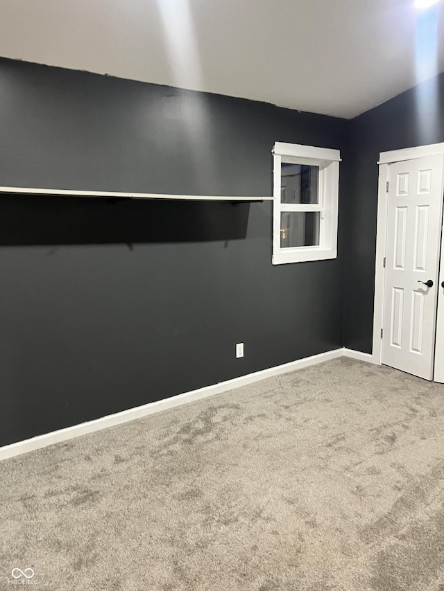 carpeted spare room with lofted ceiling