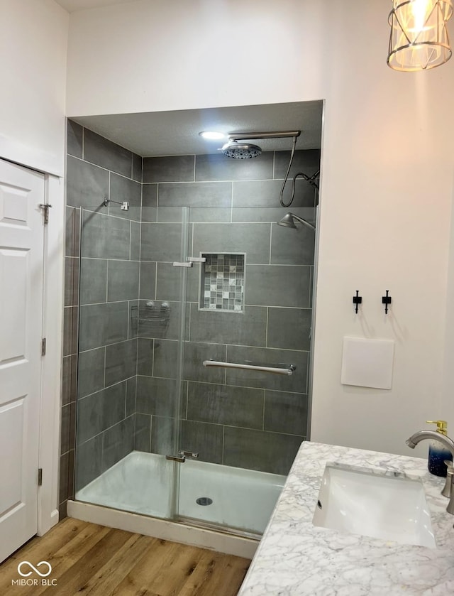 bathroom with hardwood / wood-style flooring, vanity, and a shower with shower door