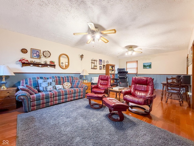 living room featuring ceiling fan, hardwood / wood-style floors, and a textured ceiling