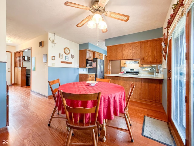 dining area with ceiling fan, sink, a textured ceiling, and light hardwood / wood-style floors