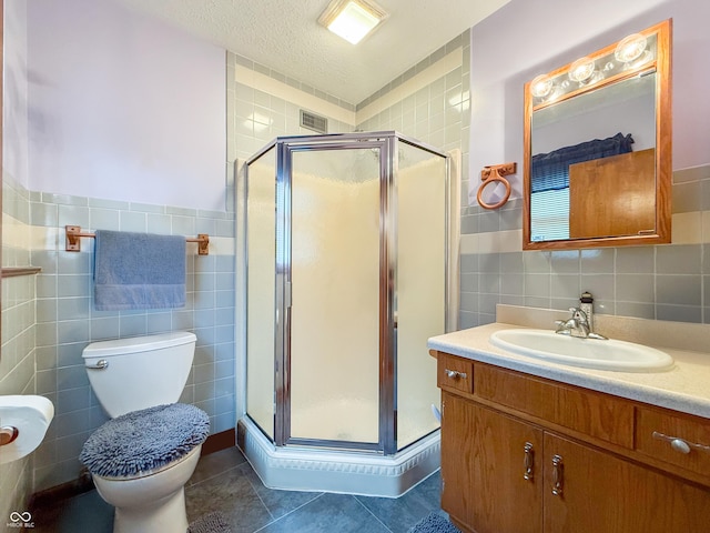 bathroom featuring a shower with shower door, tile walls, a textured ceiling, vanity, and tile patterned flooring