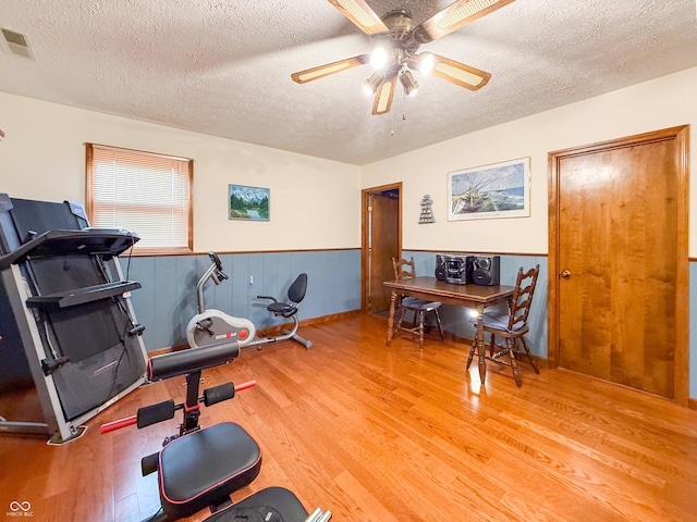 workout area with hardwood / wood-style floors, a textured ceiling, and ceiling fan