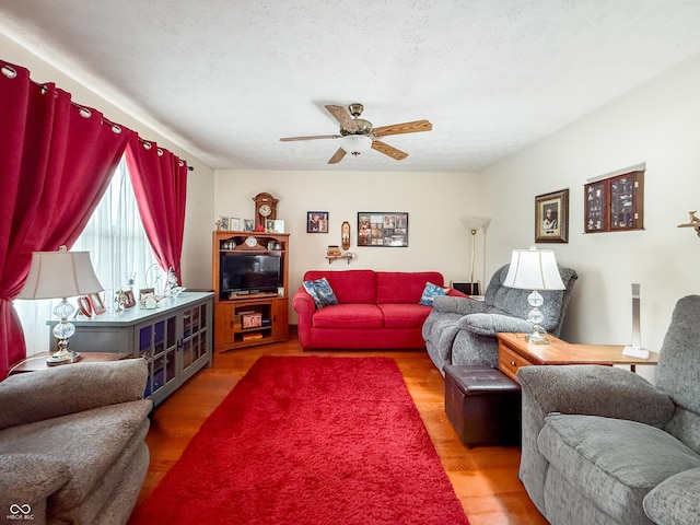 living room featuring wood-type flooring, ceiling fan, and a textured ceiling