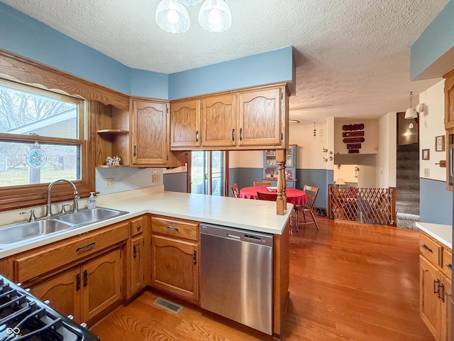 kitchen with sink, dishwasher, a textured ceiling, kitchen peninsula, and light wood-type flooring